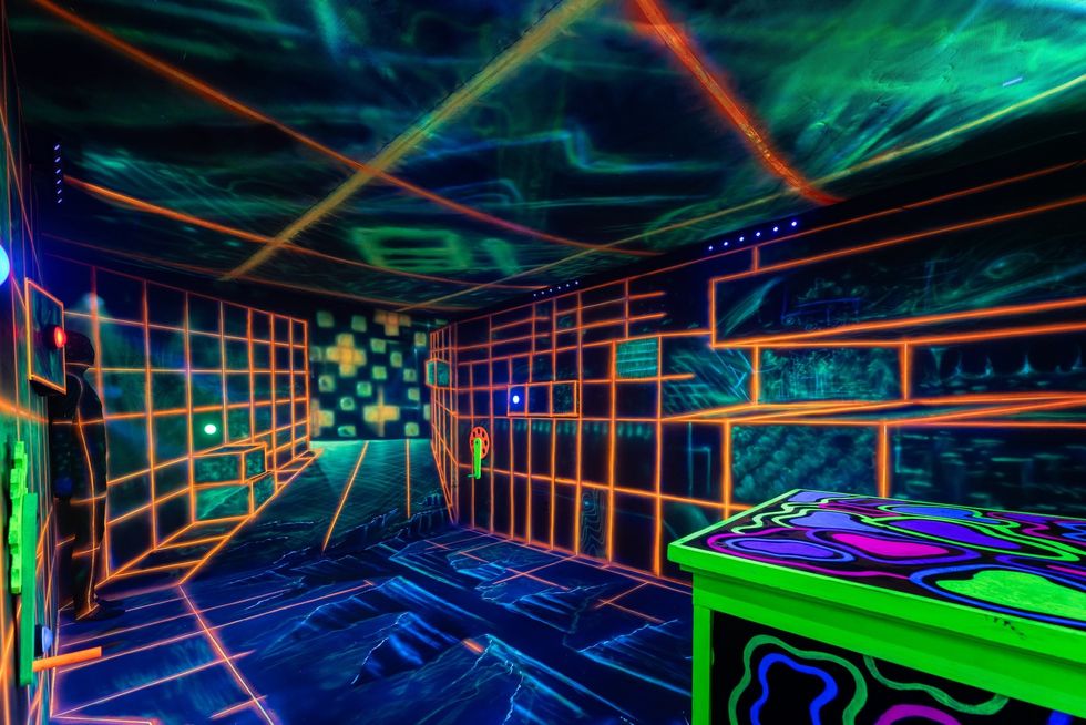 Futuristic room with neon grid lines and glowing geometric patterns on walls and floor.