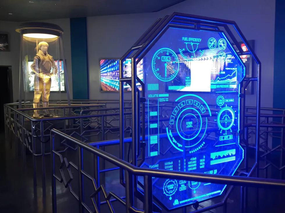 Futuristic sci-fi control panel with holographic display next to space suit exhibit, preshow for Panem Aerial Tour - Motiongate Dubai