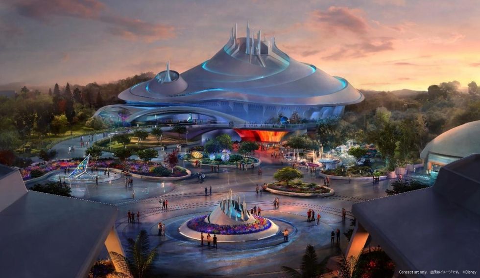 Futuristic theme park building at sunset, surrounded by colorful gardens and visitors.