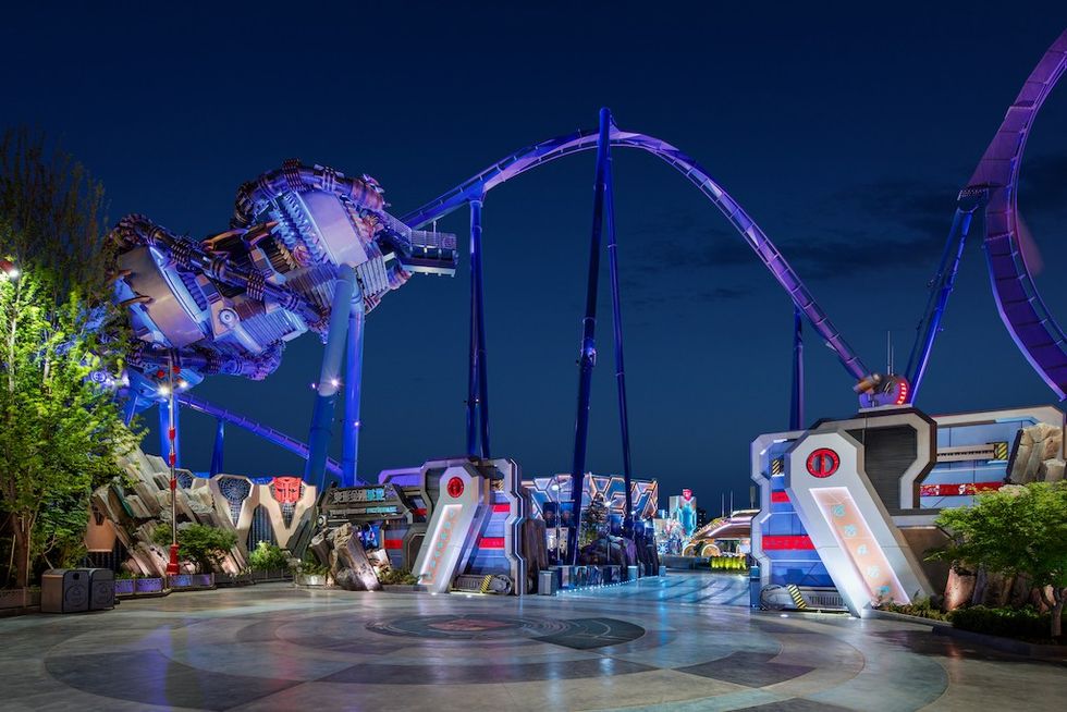 Futuristic theme park ride with purple tracks and vibrant lights at night.
