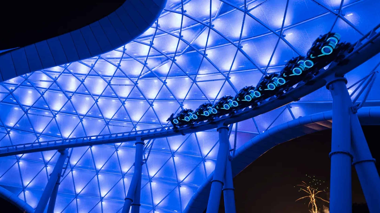 Futuristic Tron roller coaster under glowing blue lights at night.