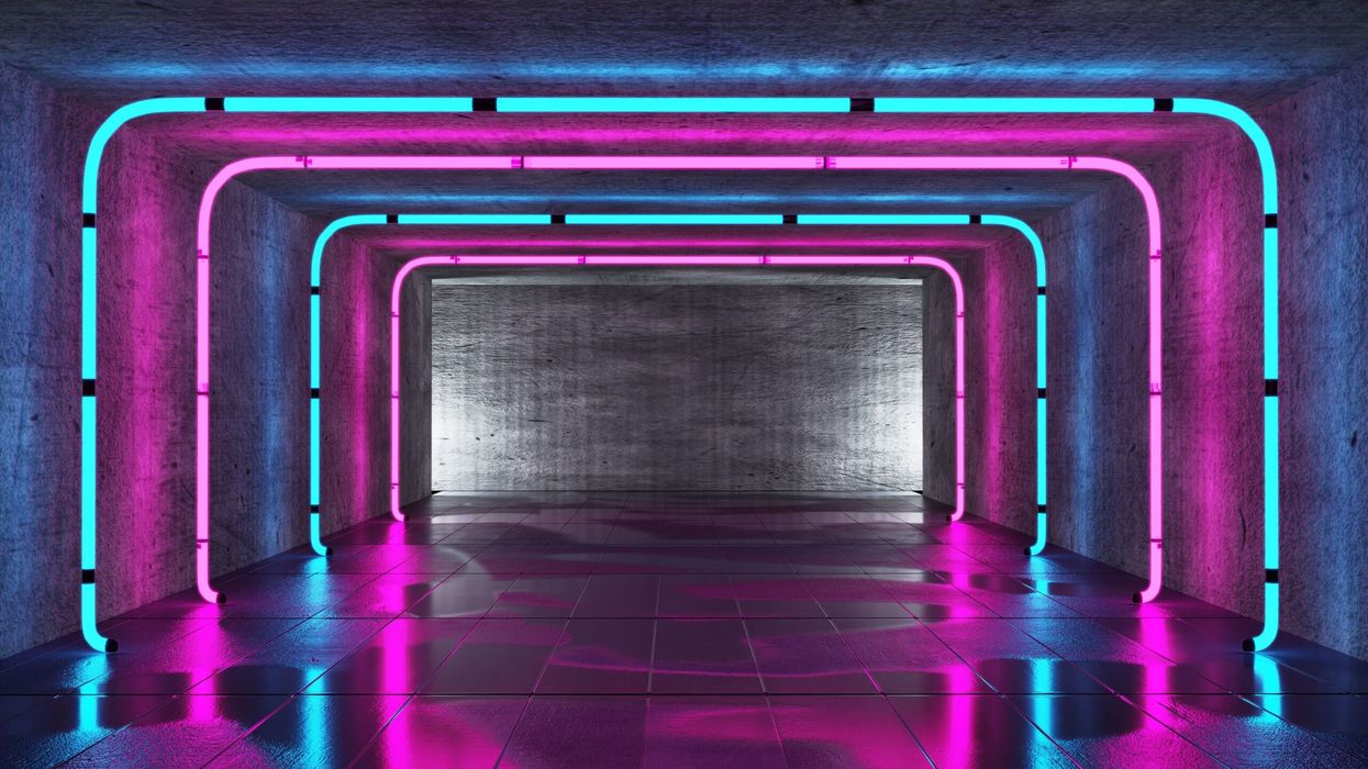 Futuristic tunnel with pink and blue neon lights on concrete walls and reflective floor.