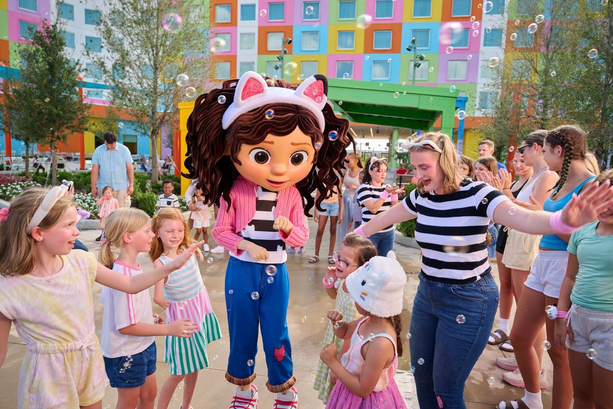 Gabby's Dollhouse mascot entertaining kids with bubbles in a colorful outdoor setting at Universal Kids Resort