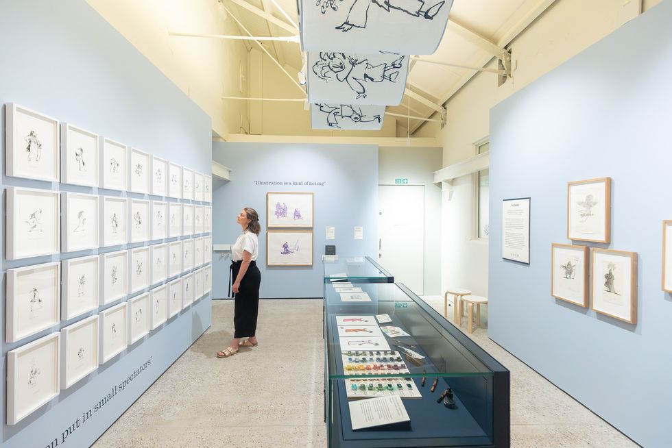 Gallery visitor at the Quentin Blake Centre for Illustration observing framed illustrations on a light blue wall.