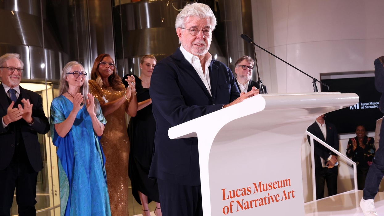 George Lucas speaks at podium, others applaud at Lucas Museum of Narrative Art event.