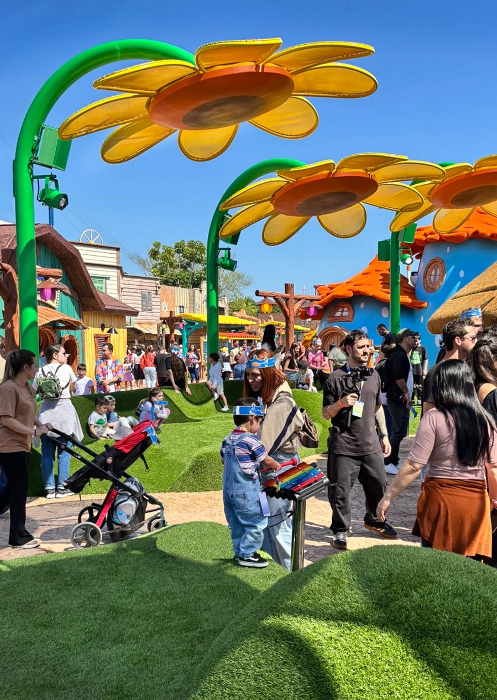 Giant flower structures and families enjoying attractions at Vila da Galinha Pintadinha at Beto Carrero World