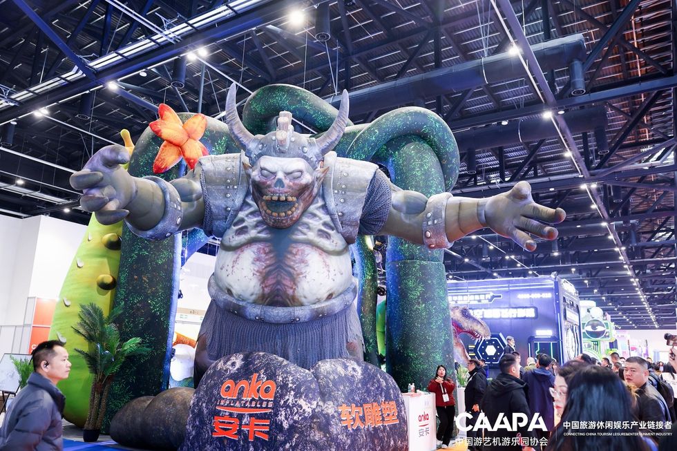 Giant horned ogre statue at a trade show with people around.