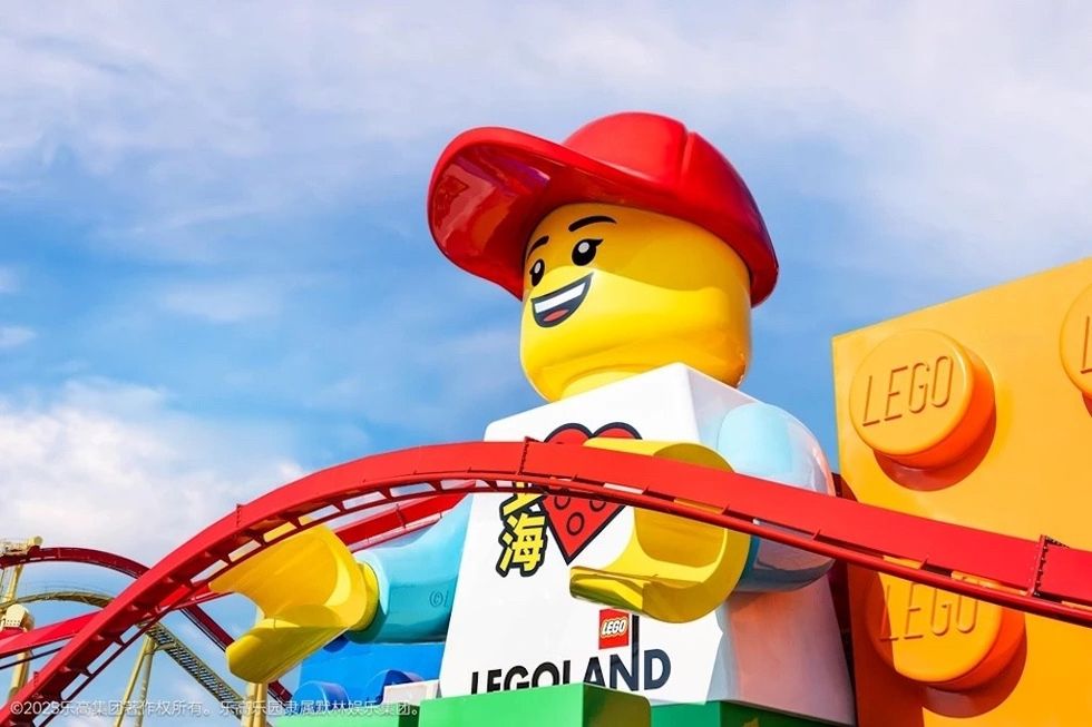 Giant LEGO figure with red cap at LEGOLAND Shanghai, under a bright blue sky.