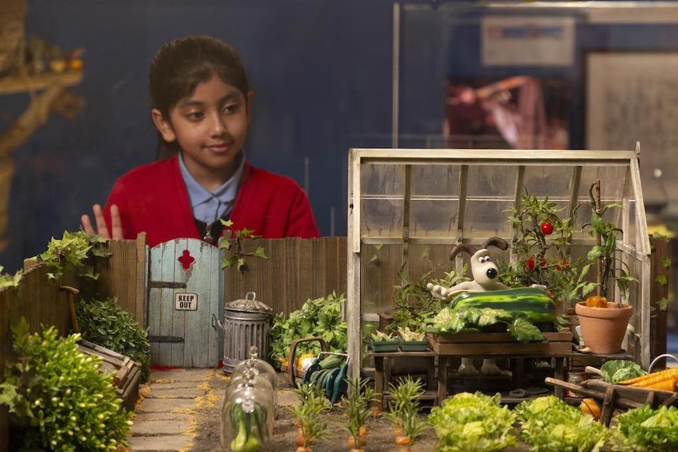 Girl at Young V&A observing a miniature garden Wallace & Gromit scene with a Gromit in a greenhouse.
