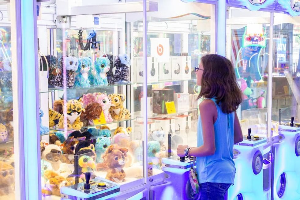 Girl playing a crane game at Tripster, by FACE Amusement