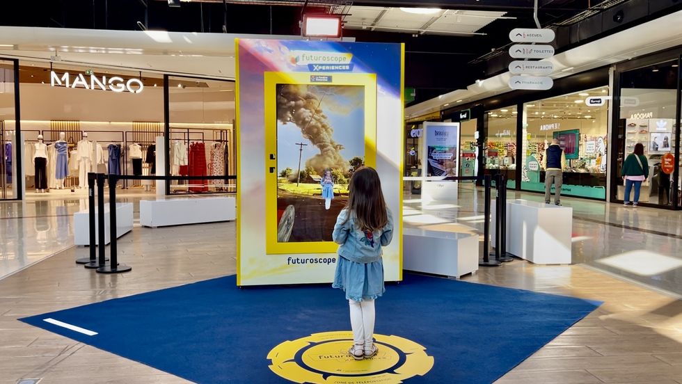 Girl watching a digital tornado display in a shopping mall.