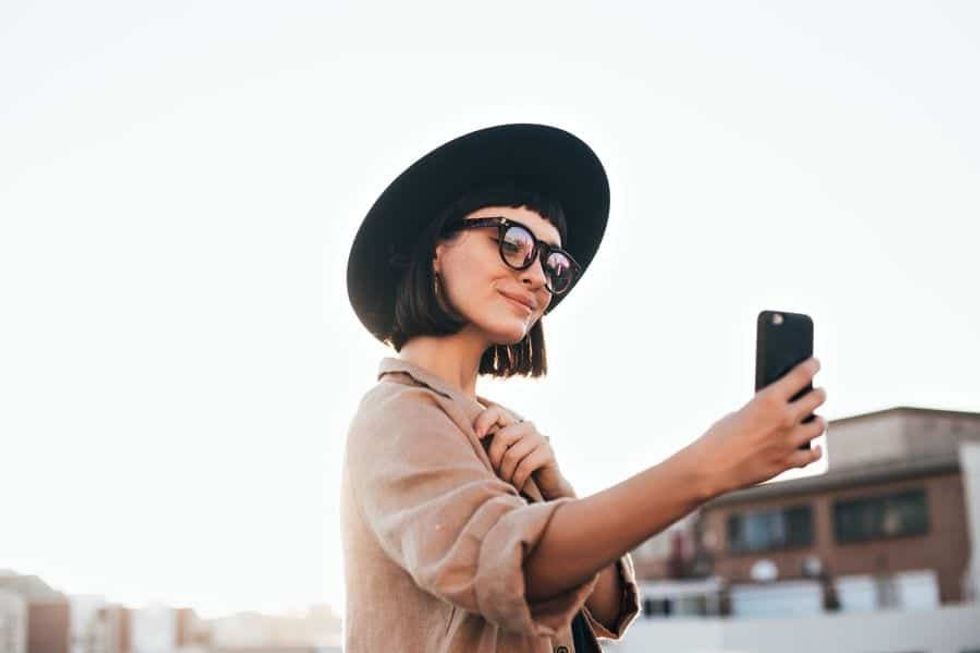 Girl with hat and glasses taking a selfie