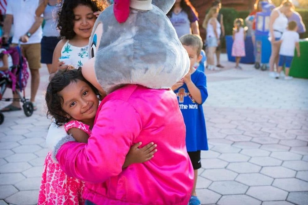 Give Kids The World Mayor Clayton mascot hugging a young girl