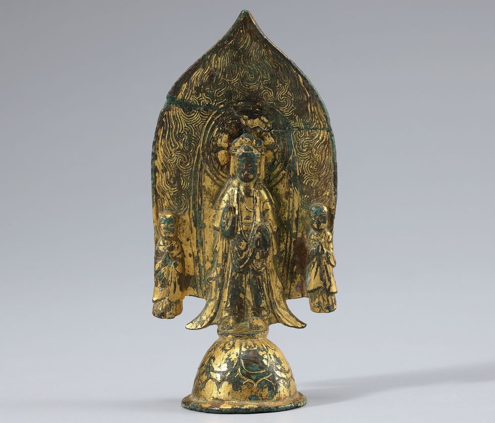 Golden Buddha statue with two attendants, intricate patterns, on smooth background.