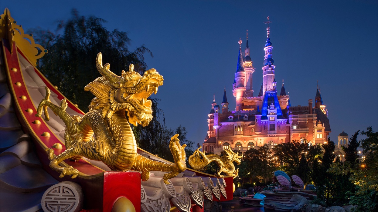 Golden dragon rooftop with illuminated castle in the background at night at Shanghai Disneyland