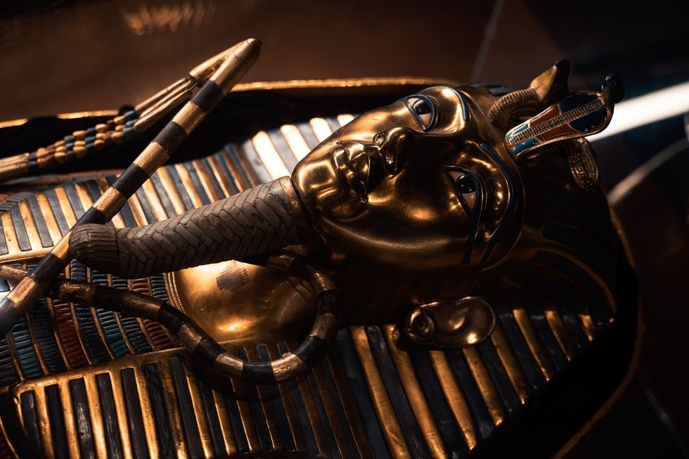 Golden Egyptian sarcophagus mask with intricate details and vibrant blue and gold accents.