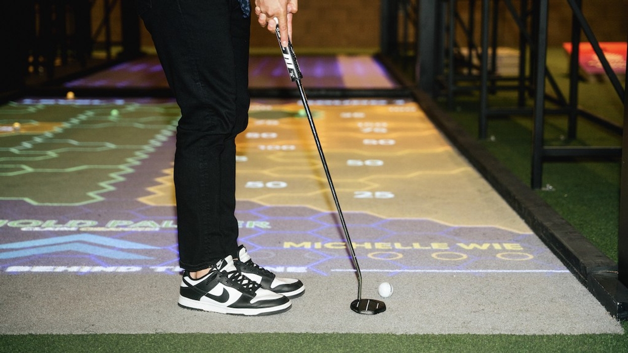 Golfer in sneakers putting on an indoor projected golf course.