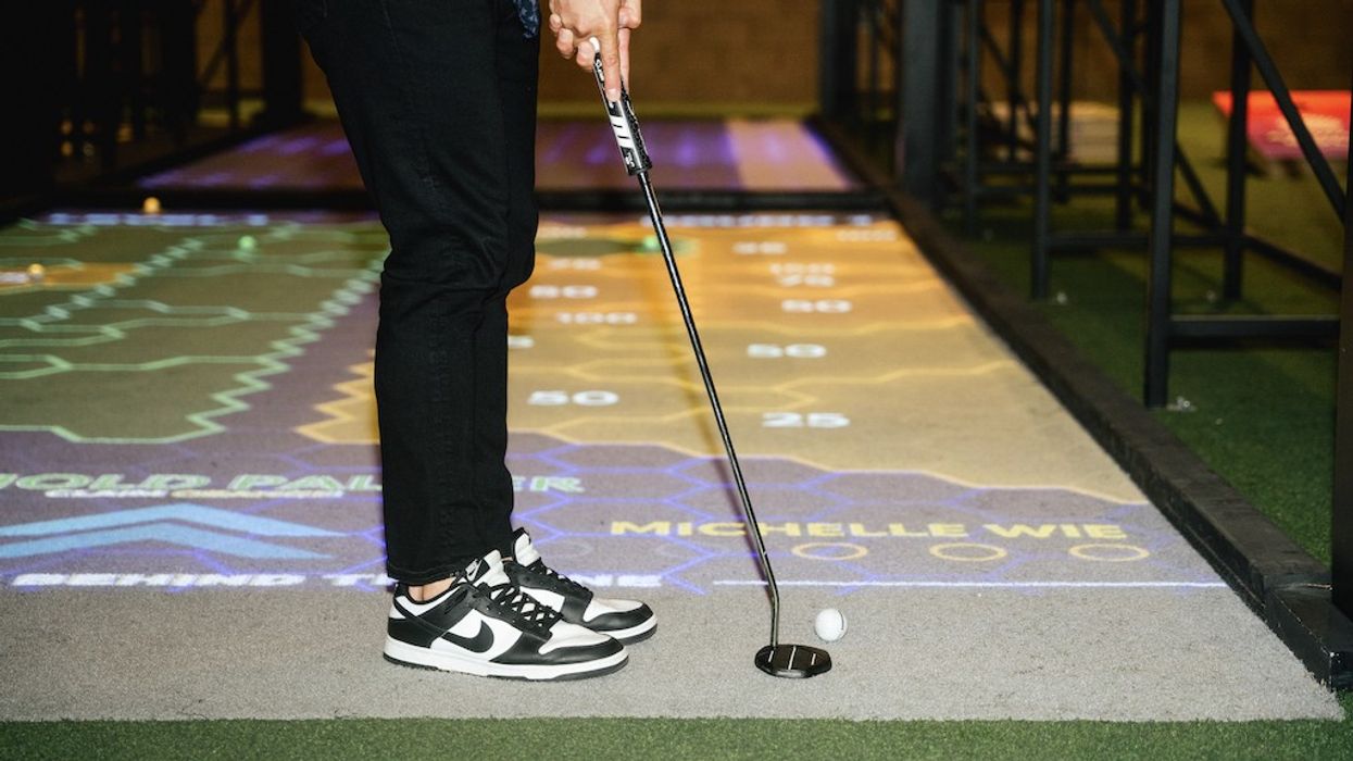 Golfer in sneakers putting on an indoor projected golf course.