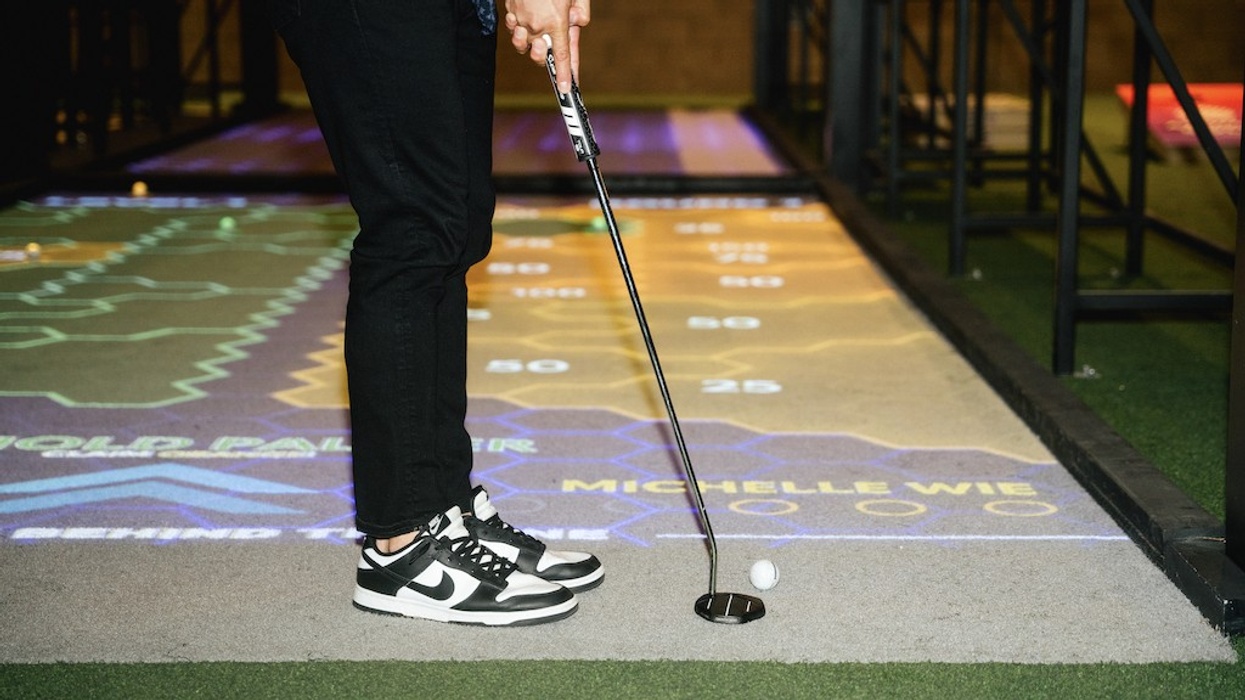 Golfer in sneakers putting on an indoor projected golf course.