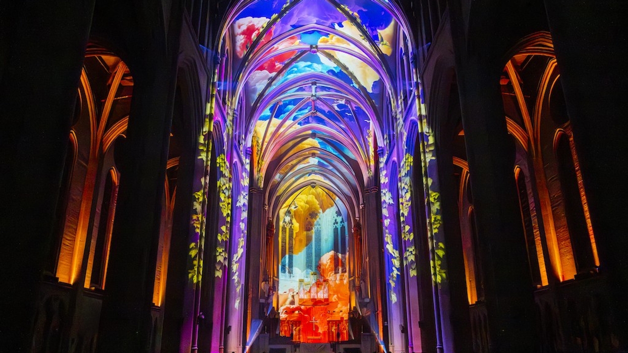 Gothic cathedral interior lit with colourful, vibrant light projections on the arches.