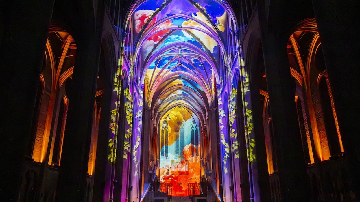 Gothic cathedral interior lit with colourful, vibrant light projections on the arches.