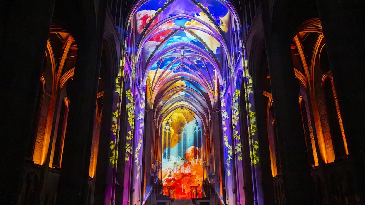 Gothic cathedral interior lit with colourful, vibrant light projections on the arches.