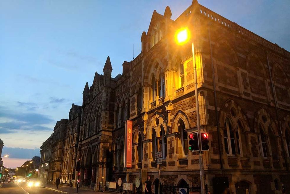 Gothic-style building at dusk with streetlights and traffic lights.