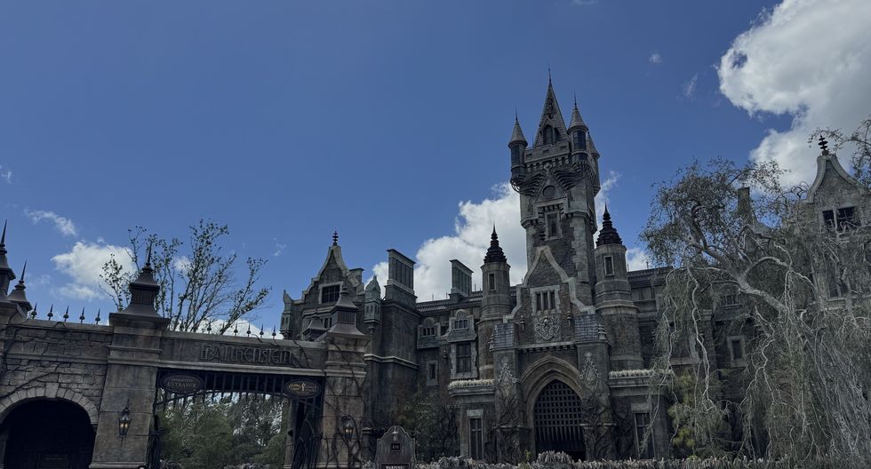 Gothic-style castle with towers and arched gate under a blue sky with clouds.