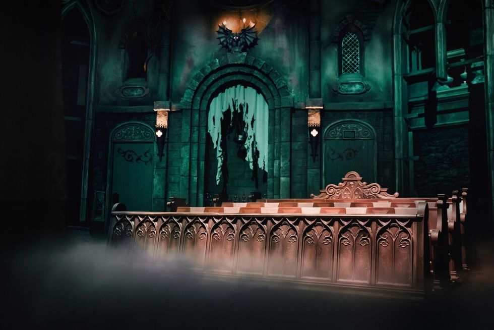 Gothic-style interior of Danse Macabre at Efteling with ornate bench seats and eerie lighting, shrouded in mist.