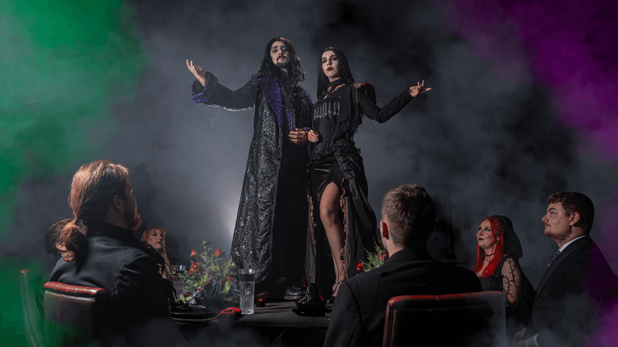Gothic-themed dinner gathering at Alton Towers with two people posing dramatically on the table.