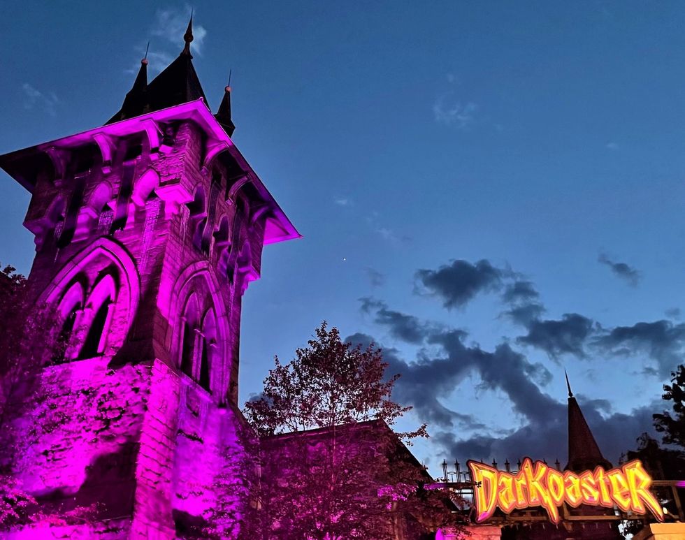 Gothic tower lit in pink at dusk with "Darkoaster" sign in foreground.