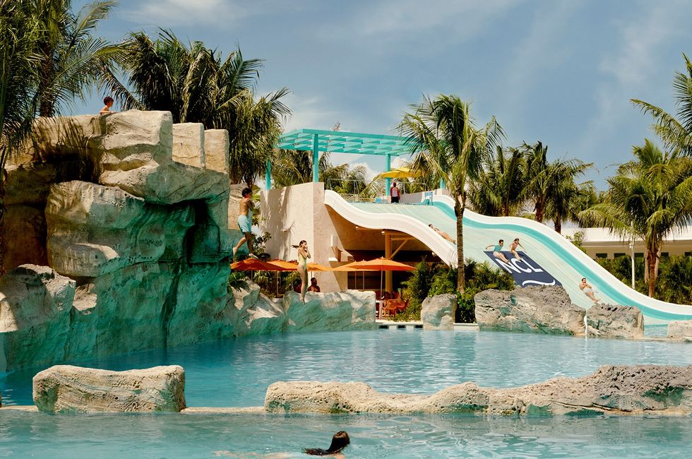 Great Tides Waterpark with slides, rocky features, and palm trees under a clear blue sky.