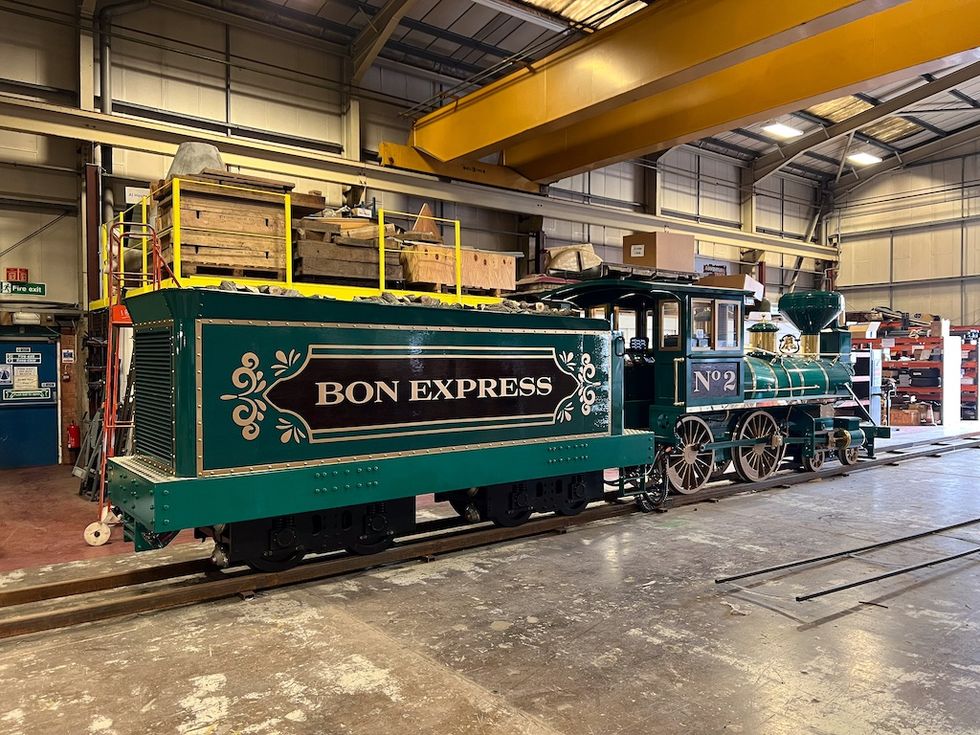 Green antique train "Bon Express" inside an industrial warehouse.