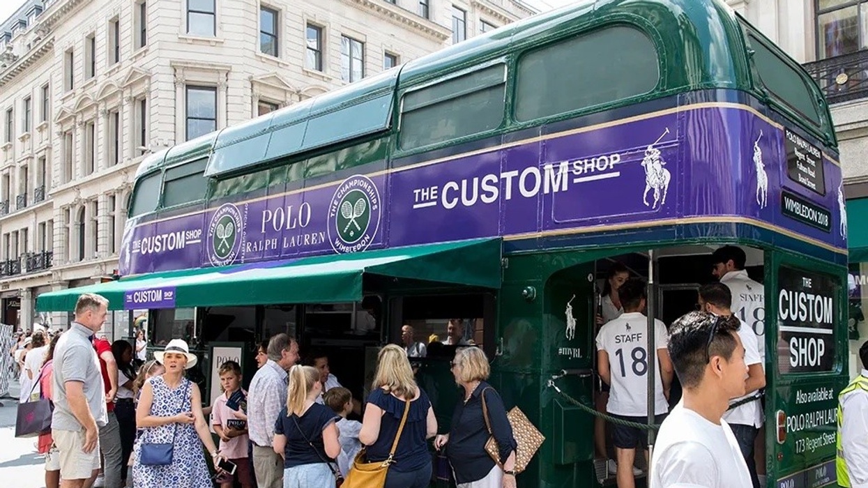 Green bus converted into a Ralph Lauren "Custom Shop" near a busy city street.