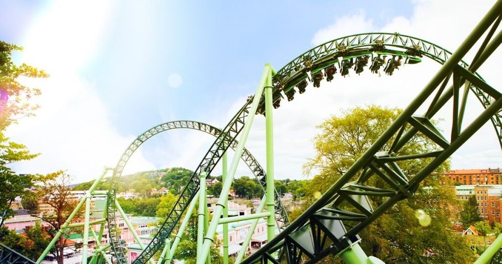 Green roller coaster loop on Helix at Liseberg with riders under a bright blue sky.