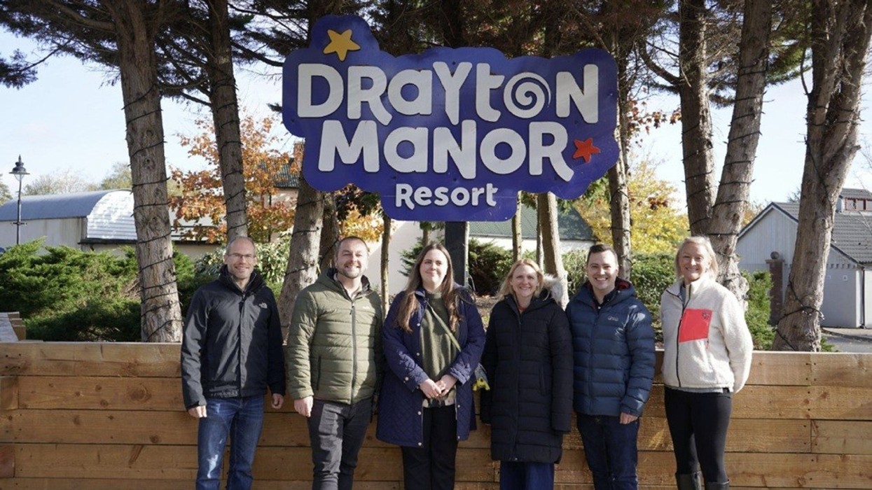 Group at Drayton Manor Resort sign with trees and buildings in the background.