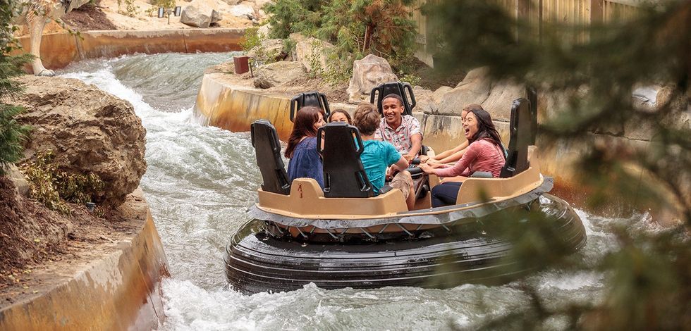 Group enjoying a raft ride on a rushing river at an amusement park.