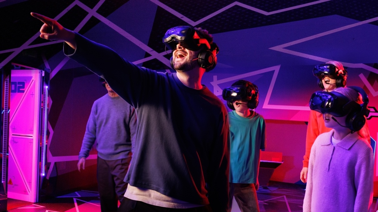 Group enjoying VR experience in colorful, immersive room, one person pointing excitedly.
