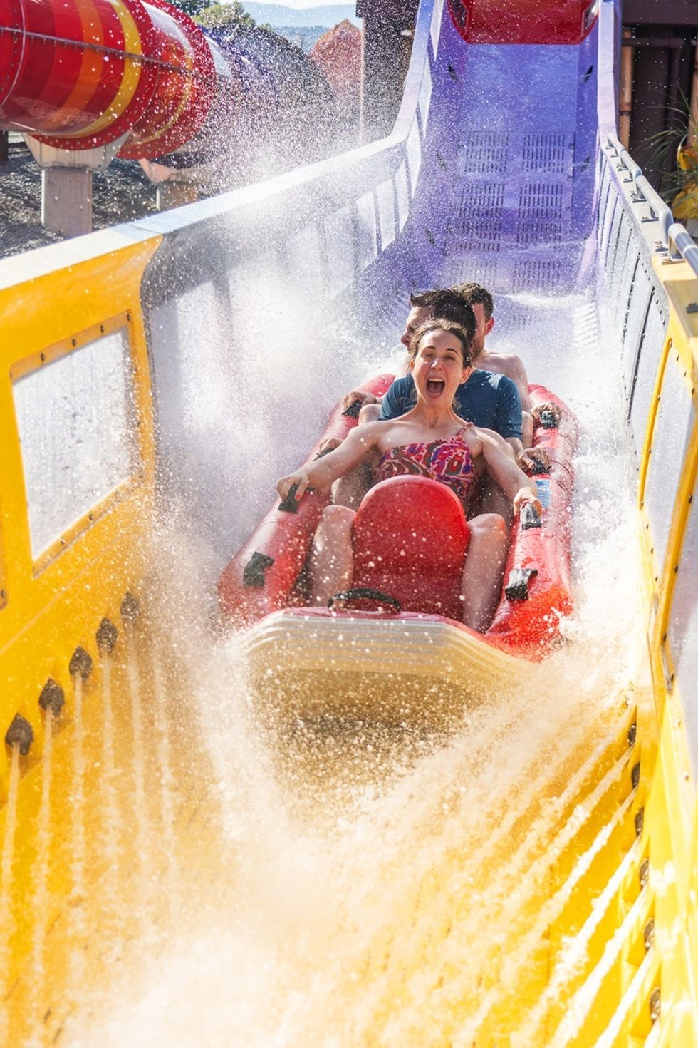Group enjoys thrilling water slide ride named Kilauea, splashing through tunnel with joyful expressions.