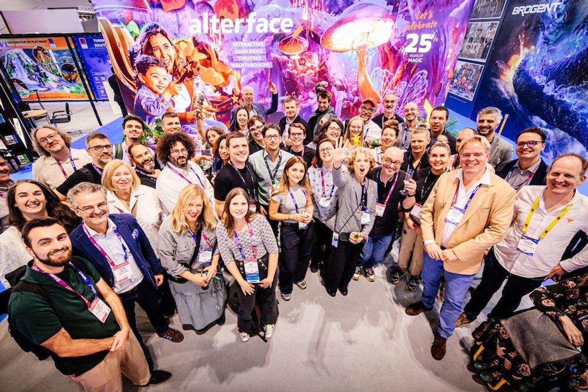 Group of diverse people smiling at a colorful event booth, celebrating Alterface's 25th anniversary together.
