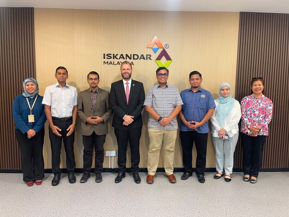 Group of eight people standing in front of Iskandar Malaysia sign.