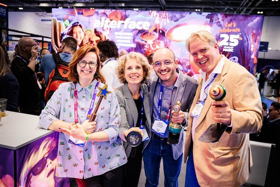 Group of four people from Alterface smiling and holding themed wands at a celebration event.