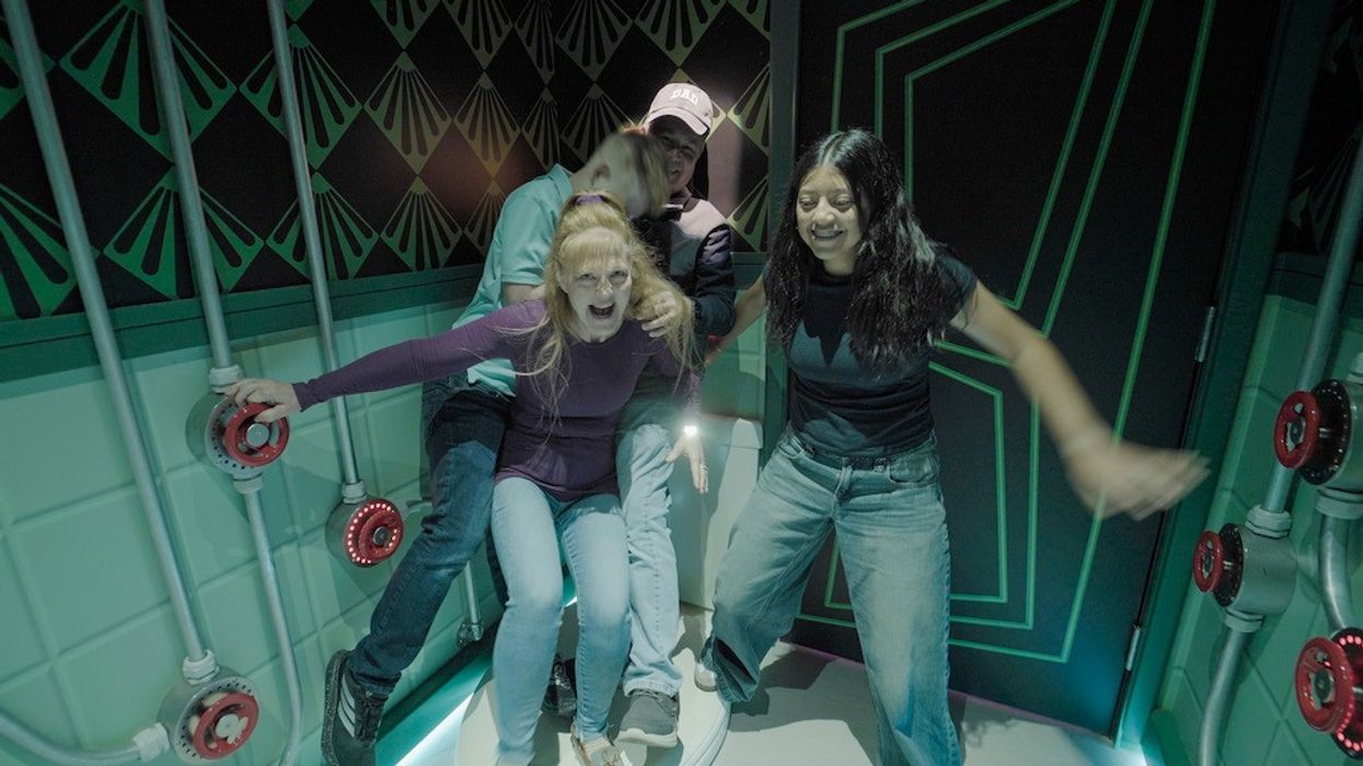 Group of four people playfully posing in a room with colorful, geometric designs.