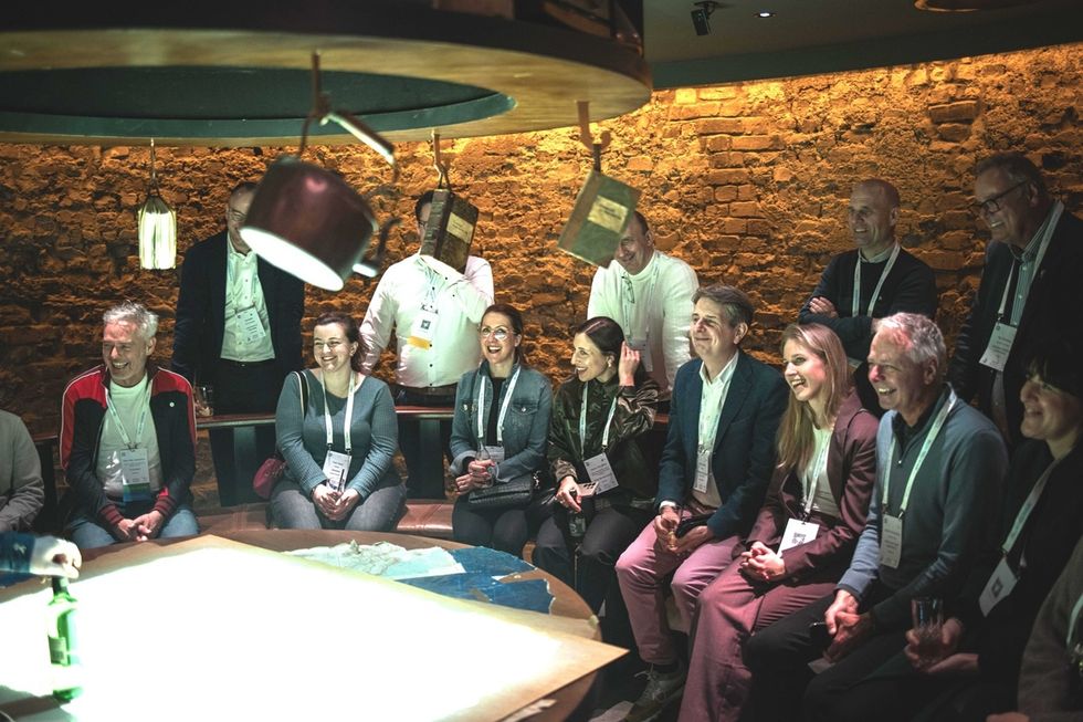 Group of people gathered around a wooden table with overhead lighting, smiling and engaged.