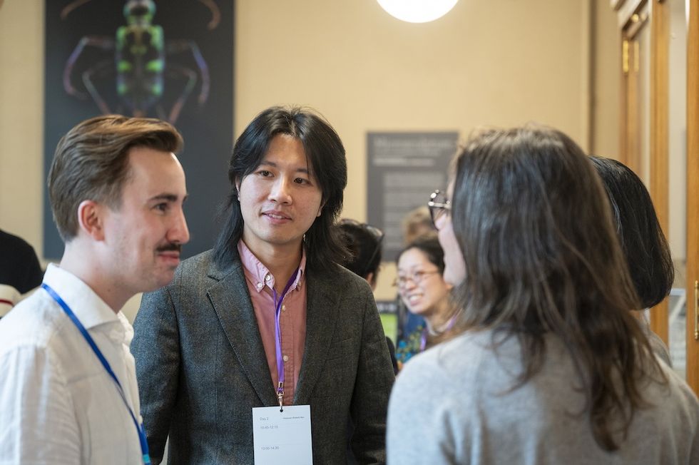 Group of people in conversation at an indoor event, one wearing a name tag.