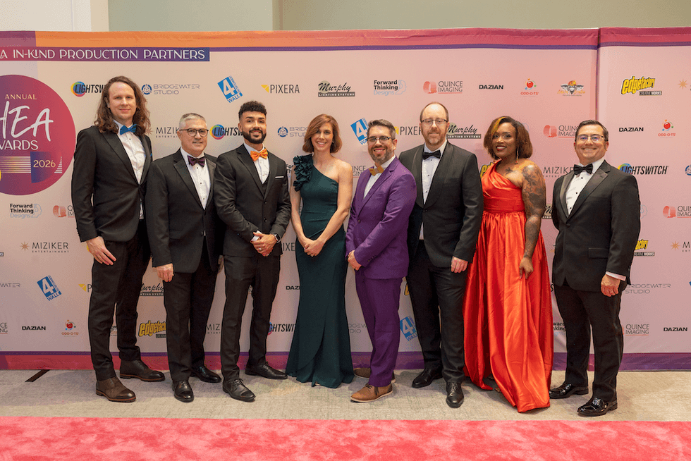 Group of people in formal attire posing on a red carpet at an awards event.