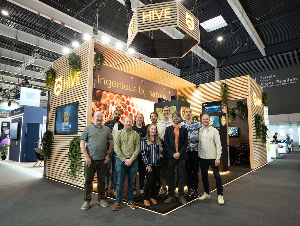 Group of people in front of the Hive exhibition booth at a convention center.