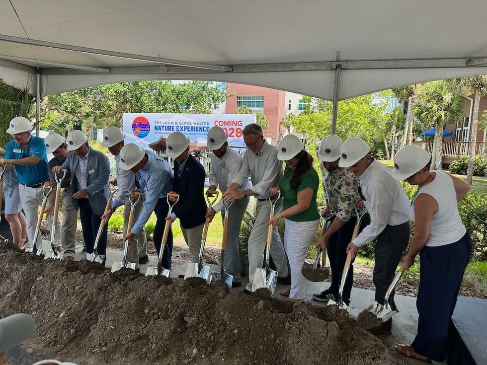 Group of people in hard hats break ground at a construction event for John and Carol Walter Nature Experience