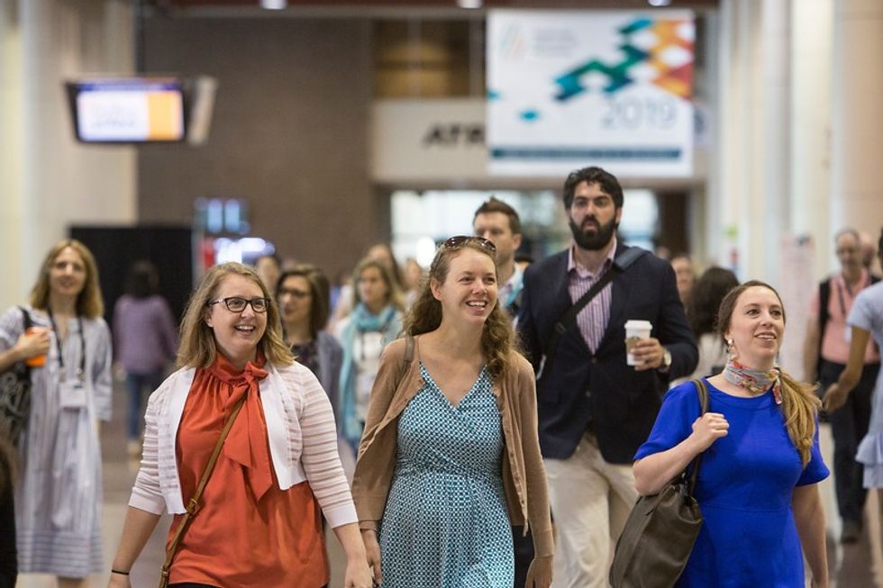 Group of people joyfully walking indoors at a conference, AAM Annual Meeting
