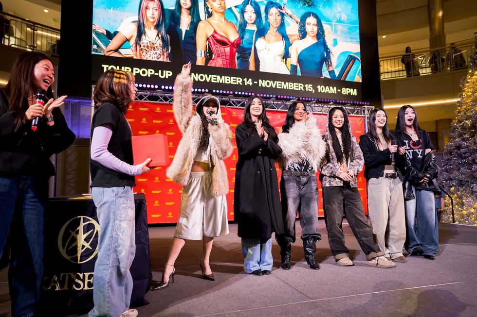 Group of people on stage at a pop-up event, with a screen and festive decor.
